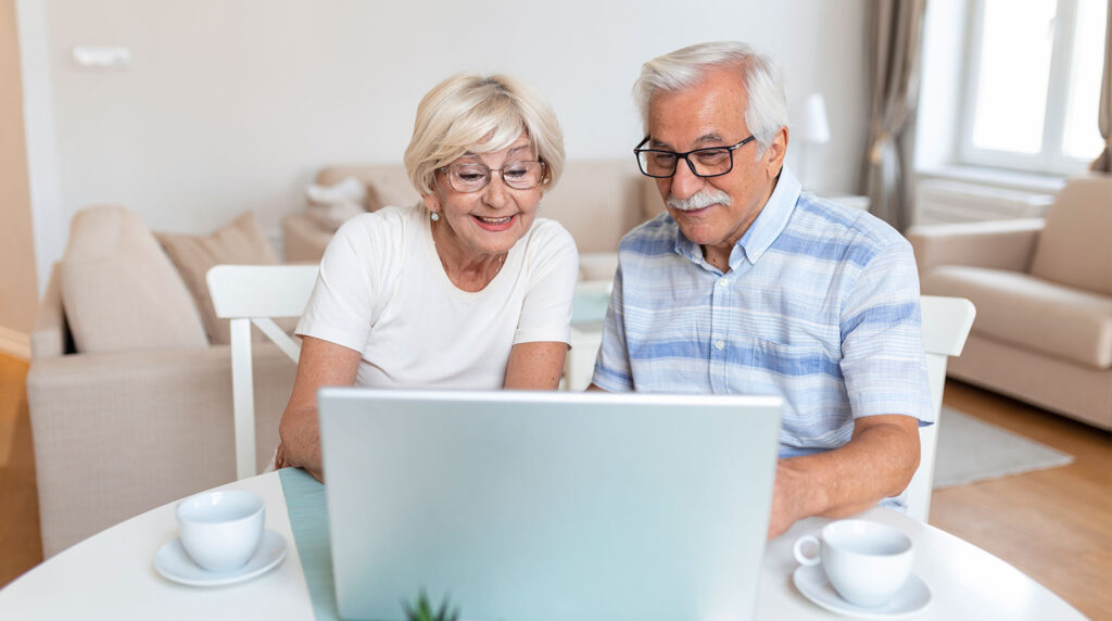 Una pareja de adultos mayores mira un ordenador en terapia de estimulación cognitiva